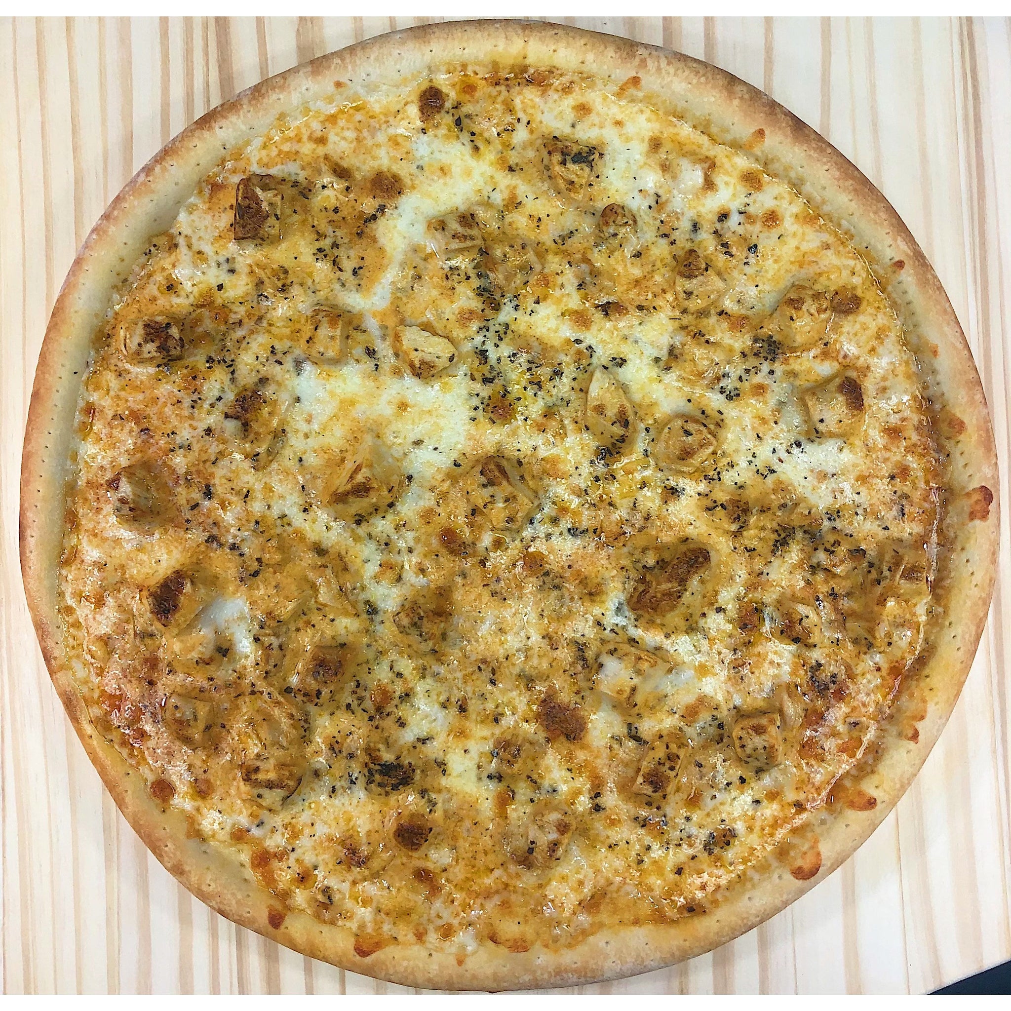 An image of a Buffalo Chicken Pizza. The pizza has a thin and crispy crust topped with zesty Buffalo sauce. It is generously covered with seasoned grilled chicken pieces, melted cheese, and thinly sliced red onions. The pizza is finished with a drizzle of ranch or blue cheese dressing and a sprinkle of fresh cilantro. The combination of spicy Buffalo flavors, savory chicken, and melted cheese creates a mouthwatering pizza.